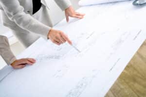 Close-up of hands of female architects working on blueprint.